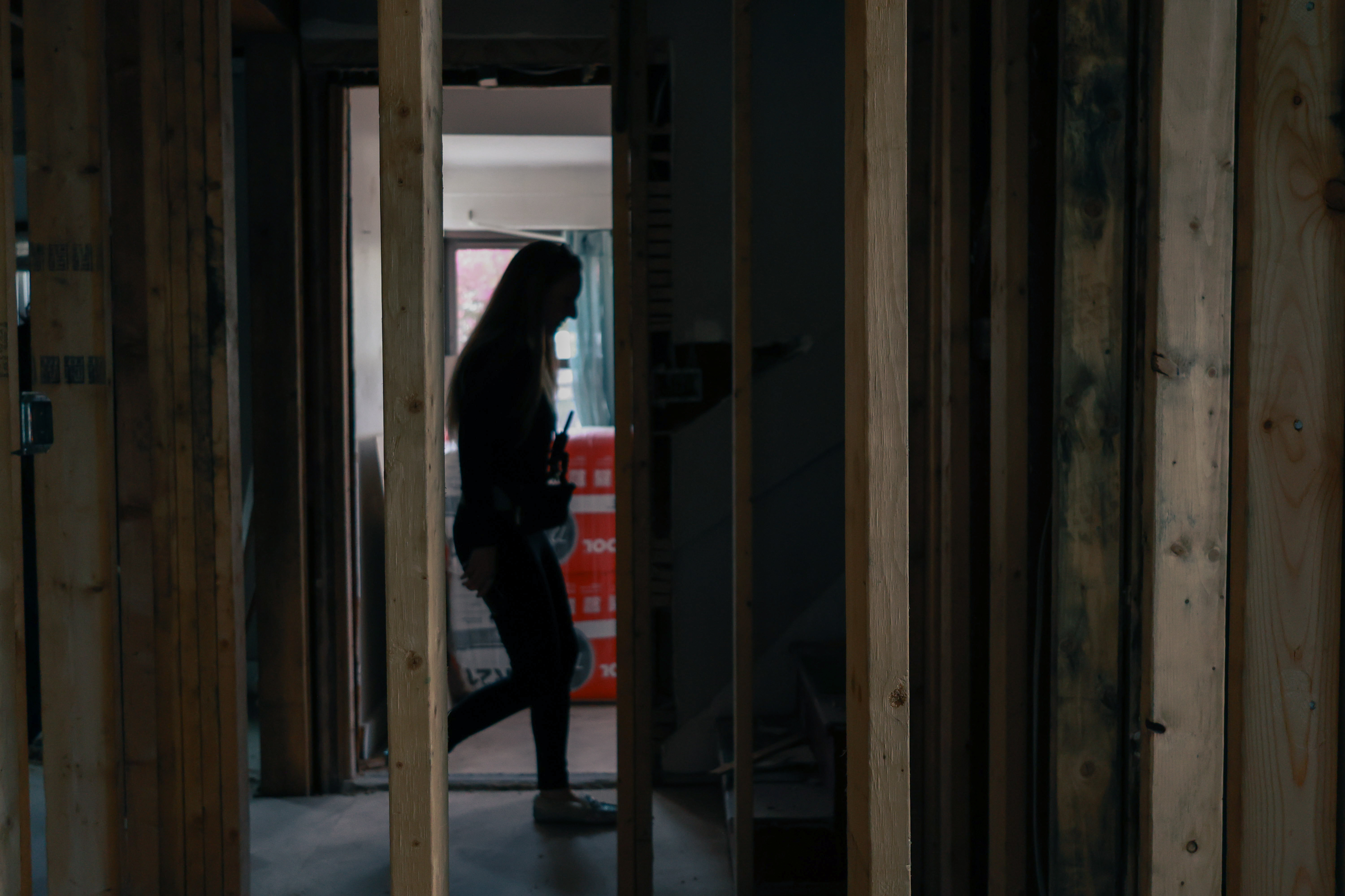 Photo of a silhouette of a woman walking between wooden support beams.